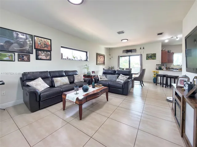 a living room with furniture and a view of kitchen