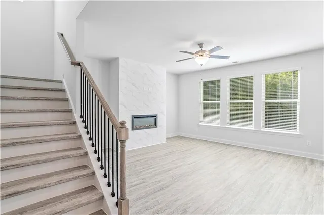 a view of an empty room with wooden floor and a ceiling fan