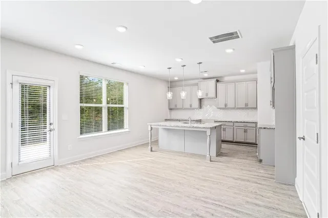 a large white kitchen with kitchen island a sink stainless steel appliances and cabinets