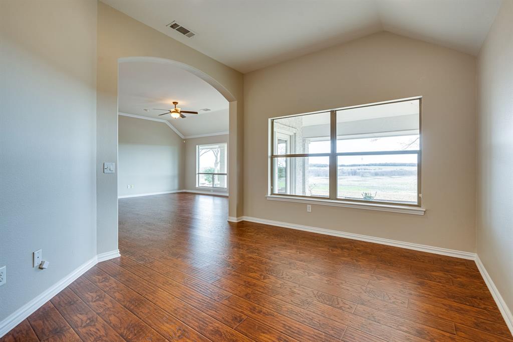 9109 Perimeter Street Denton, TX 76207 - Photo 12 of 27 Empty room featuring vaulted ceiling, dark wood-type flooring, ceiling fan, arched walkways, and crown molding
