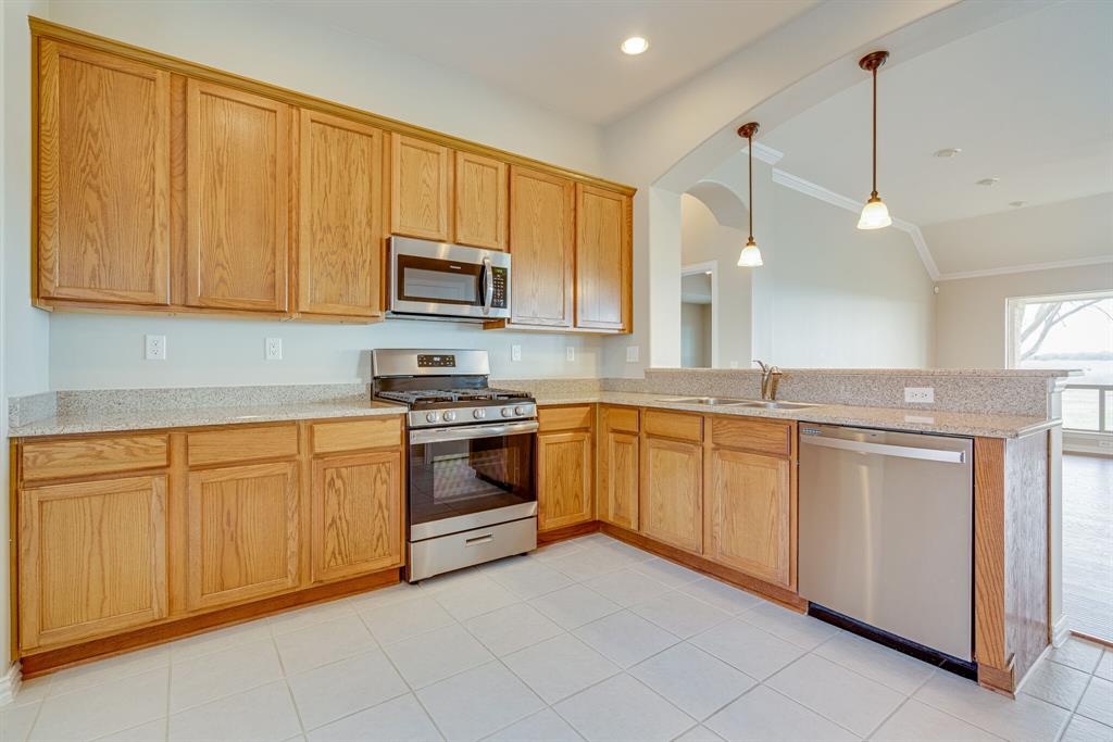 9109 Perimeter Street Denton, TX 76207 - Photo 14 of 27 Kitchen featuring appliances with stainless steel finishes, light tile patterned floors, pendant lighting, vaulted ceiling, and a peninsula