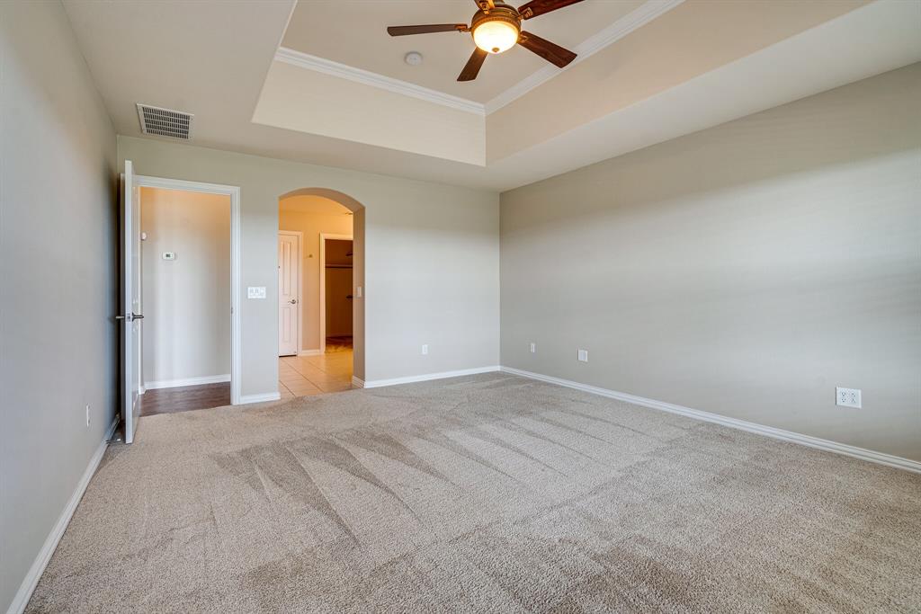 9109 Perimeter Street Denton, TX 76207 - Photo 19 of 27 Empty room featuring a raised ceiling, arched walkways, light carpet, crown molding, and a ceiling fan