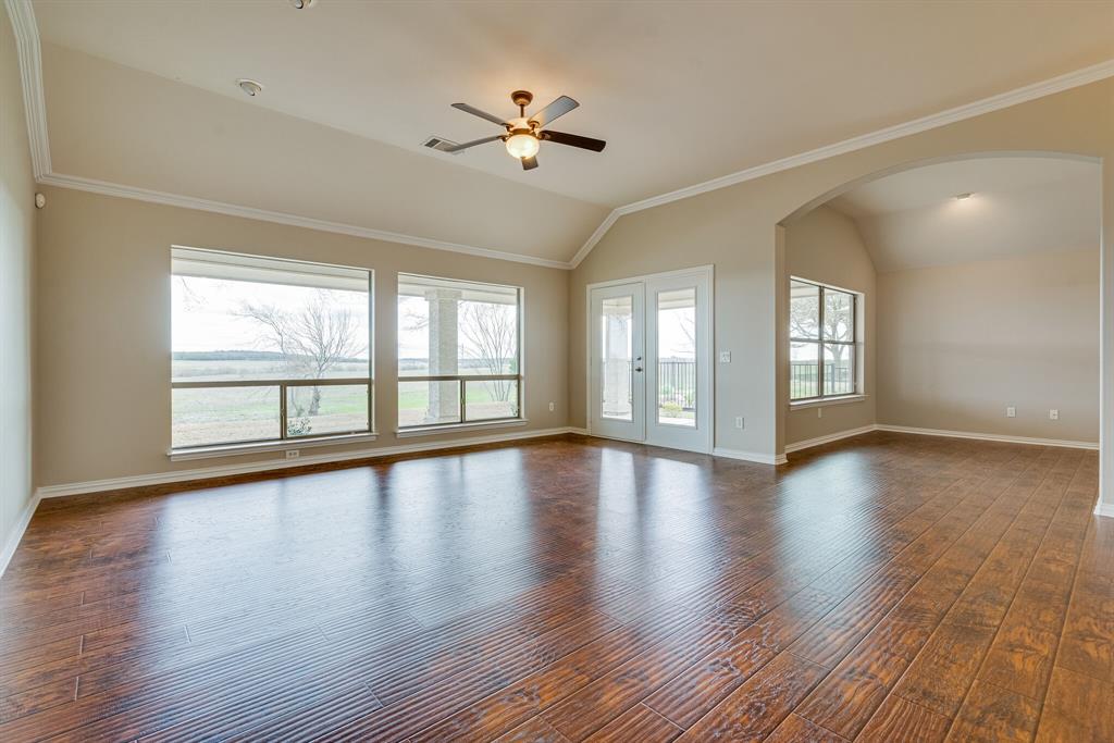 9109 Perimeter Street Denton, TX 76207 - Photo 8 of 27 Empty room with arched walkways, dark wood-style floors, lofted ceiling, crown molding, and ceiling fan