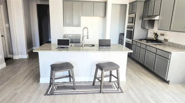 a kitchen with stainless steel appliances granite countertop a table chairs sink and cabinets