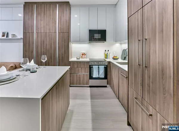 a kitchen with stainless steel appliances a stove top oven a sink dishwasher and microwave with wooden floor