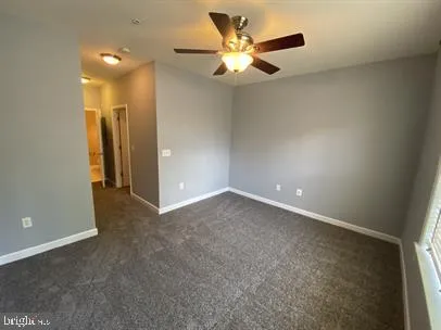 an empty room with a fan & a window