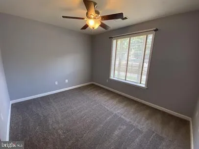 an empty room with a window and a fan
