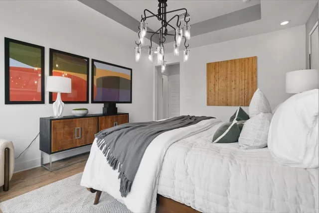 a bedroom with a bed a chandelier and dresser