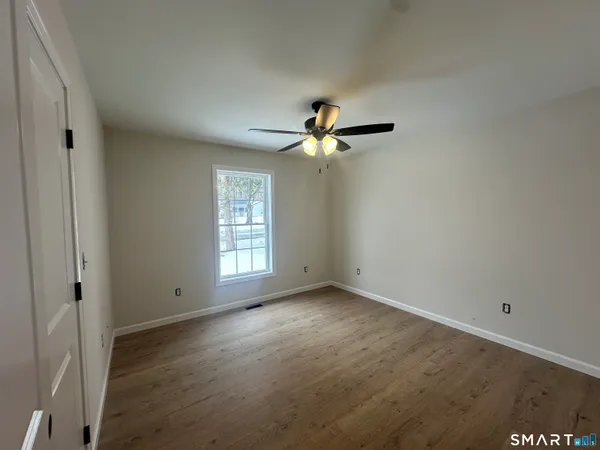an empty room with wooden floor and ceiling fan