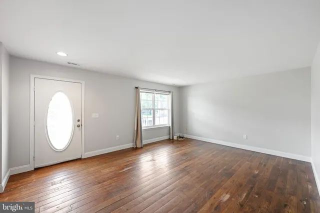 an empty room with wooden floor and window