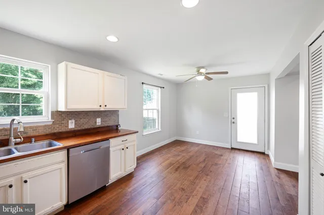a kitchen with granite countertop a sink wooden floor and window