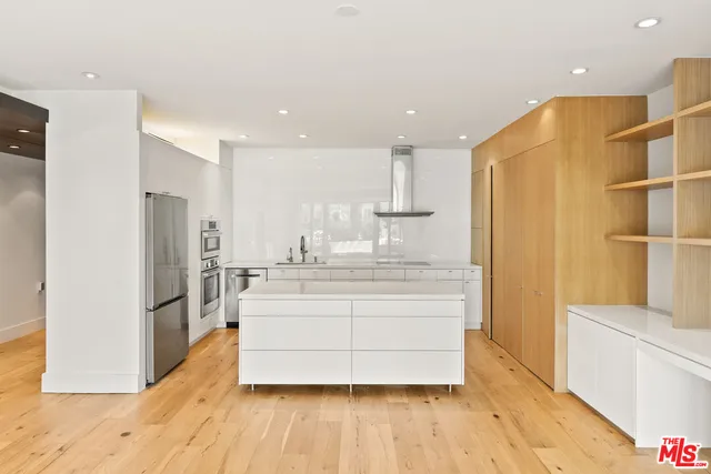 a large white kitchen with wooden floor and a refrigerator