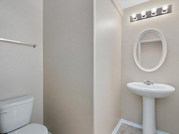 904 Lonesome Lilly Way Pflugerville, TX 78660 - Photo 14 of 34 The bathroom features a white pedestal sink, an oval mirror, and a modern light fixture with four bulbs