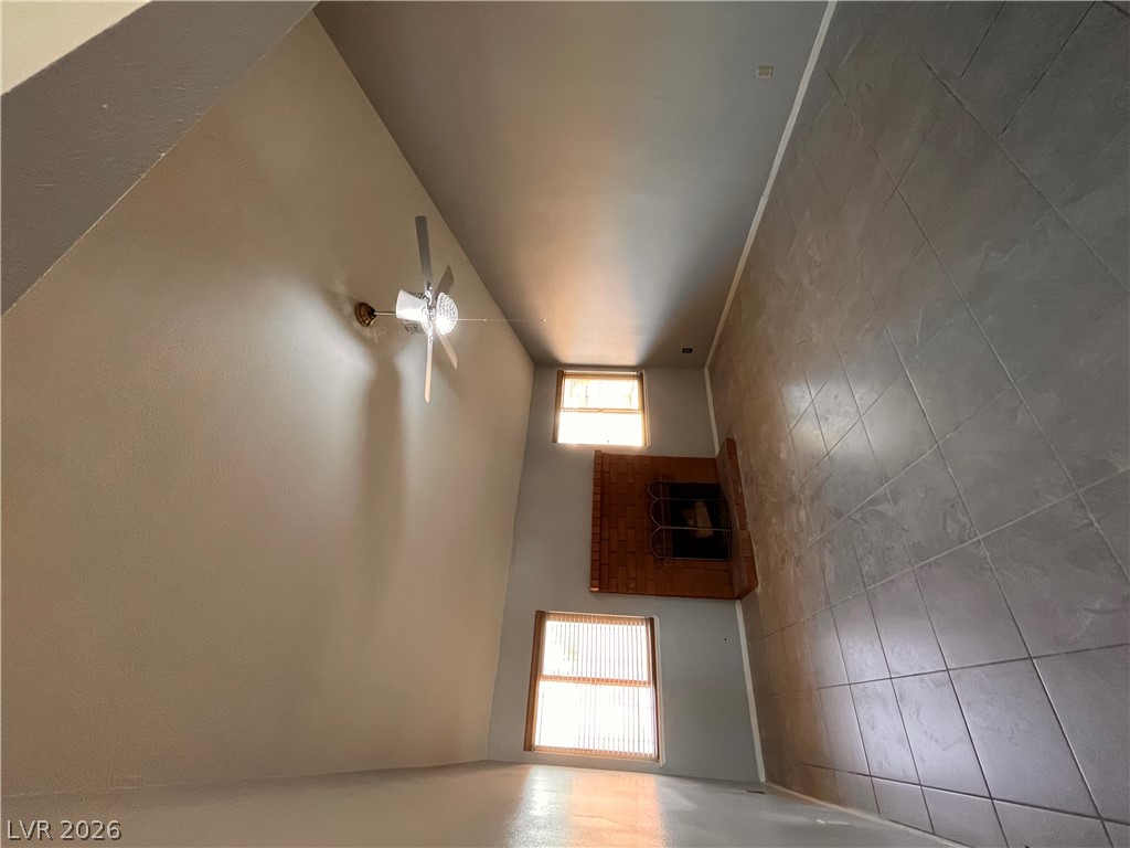 5348 Ravendale Circle Las Vegas, NV 89120 - Photo 10 of 14 A spacious room features soaring vaulted ceilings and a warm brick fireplace for cozy evenings.