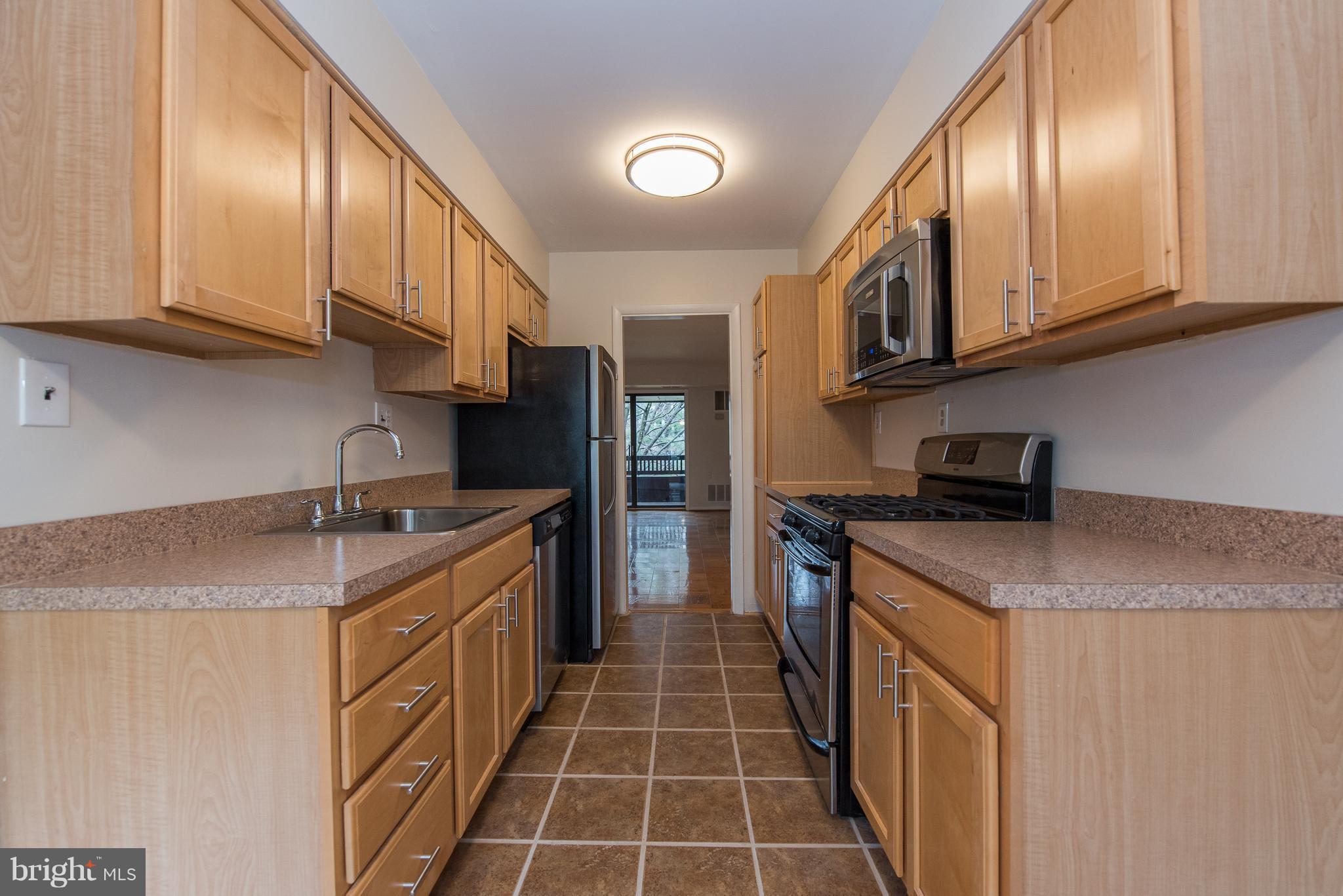5232 West Running Brook Road, Unit 301 Columbia, MD 21044 - Photo 7 of 29 a kitchen with stainless steel appliances granite countertop a sink stove and refrigerator