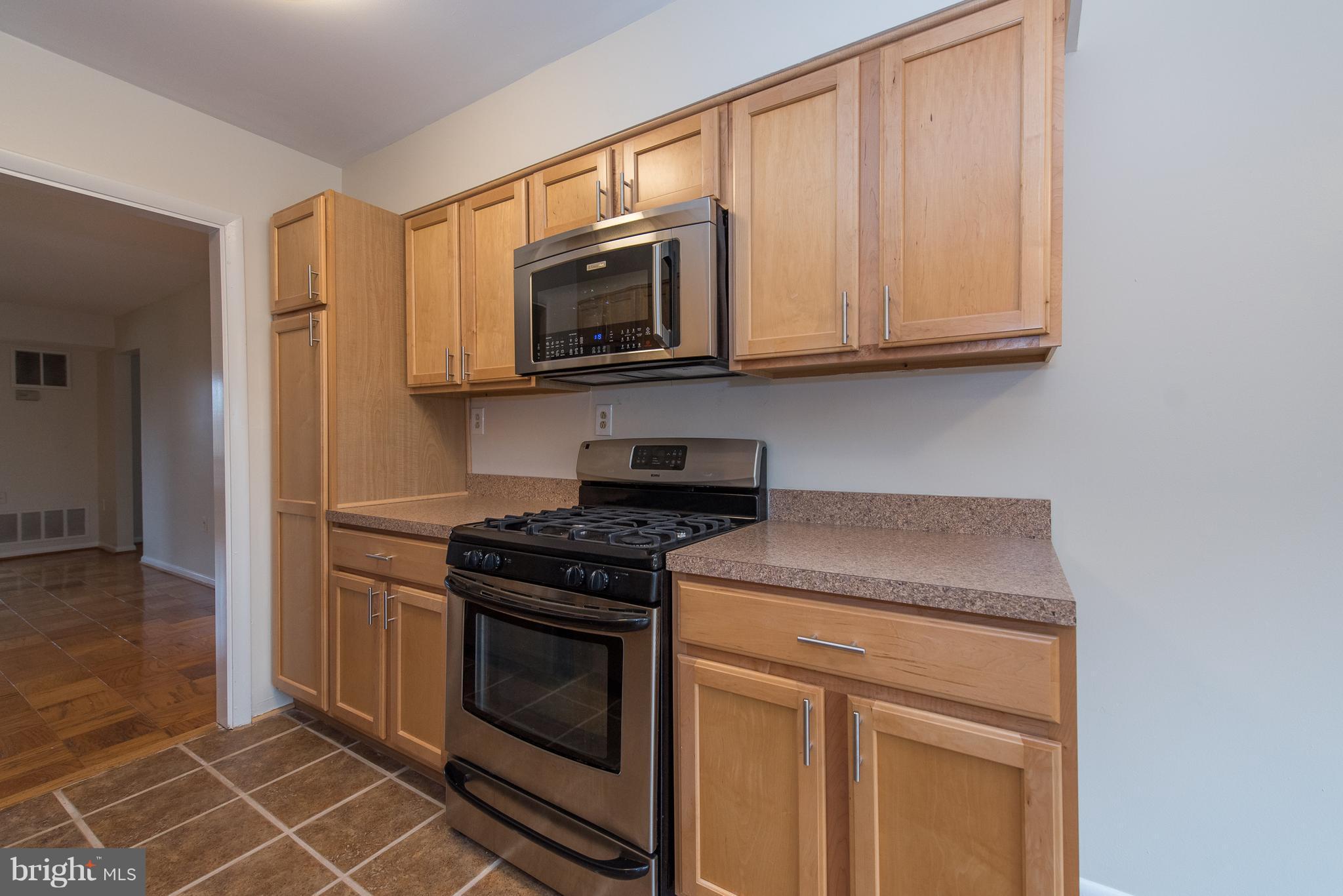 5232 West Running Brook Road, Unit 301 Columbia, MD 21044 - Photo 9 of 29 a kitchen with stainless steel appliances granite countertop white cabinets and a stove top oven