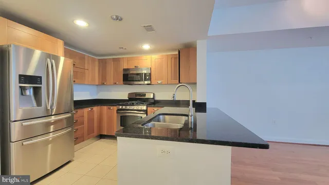 a kitchen with stainless steel appliances granite countertop a refrigerator a stove a sink and a microwave