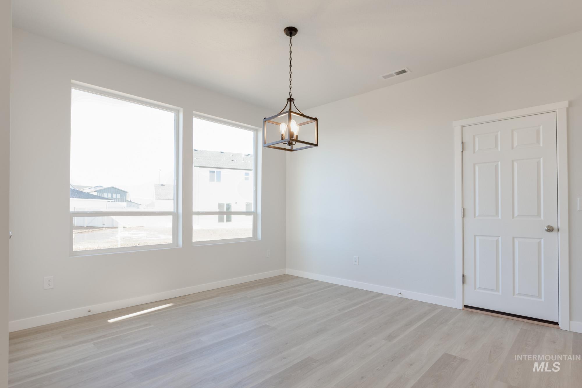 1639 Celina Street Middleton, ID 83644 - Photo 5 of 19 Bright interior space featuring three large windows, light wood-finish flooring, and a contemporary black metal chandelier
