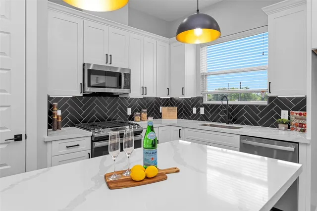 a kitchen with stainless steel appliances granite countertop a sink a stove cabinets and a window