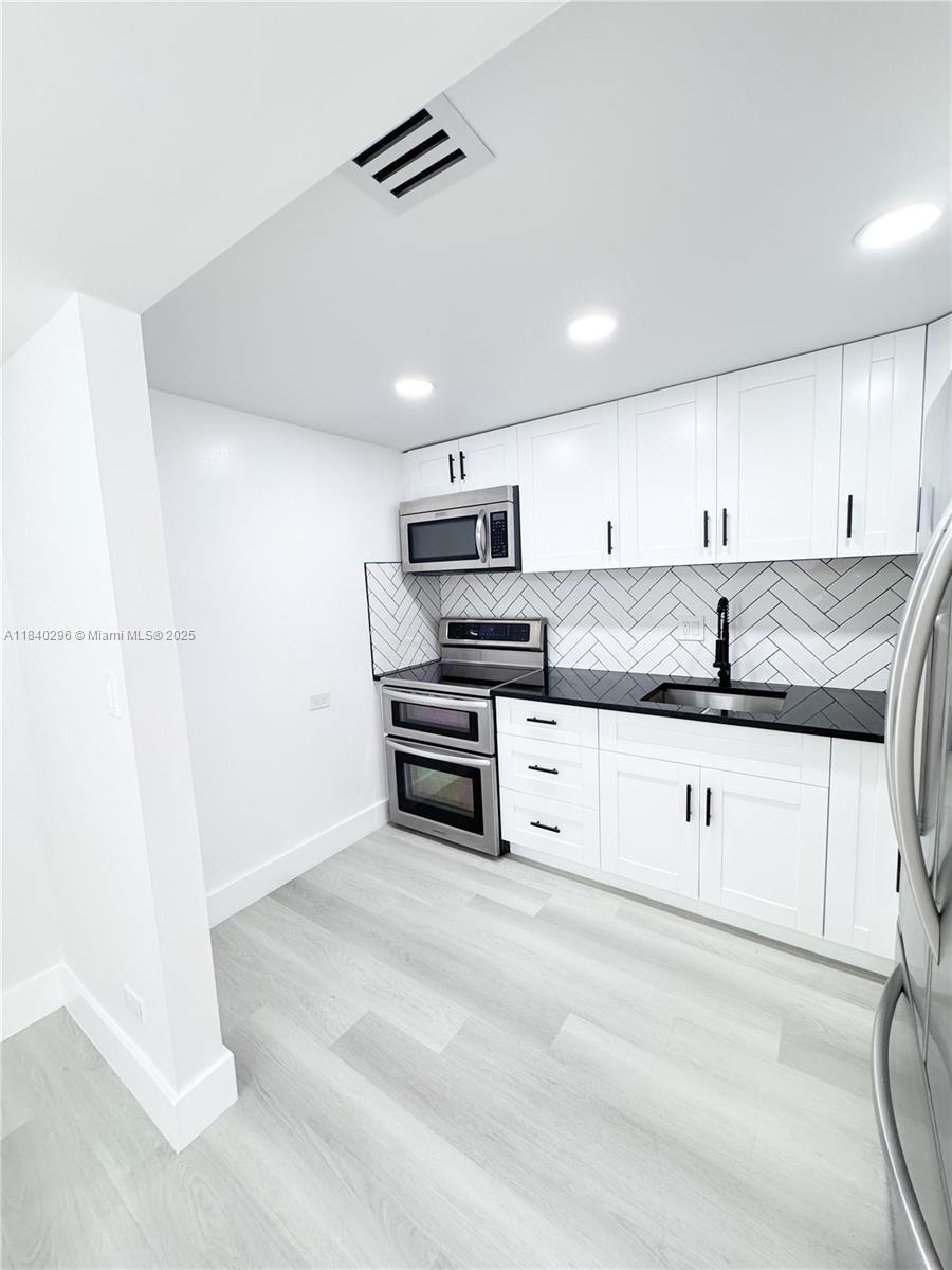 3660 Inverrary Drive, Unit 1Y Lauderhill, FL 33319 - Photo 3 of 24 a kitchen with granite countertop white cabinets and stainless steel appliances