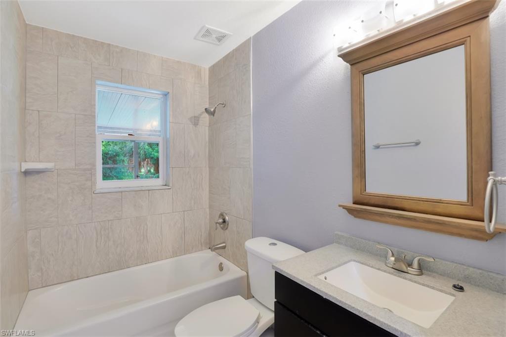 19109 Birch Road Fort Myers, FL 33967 - Photo 19 of 24 a bathroom with a sink vanity mirror bathtub and toilet
