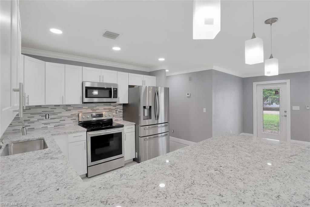 19109 Birch Road Fort Myers, FL 33967 - Photo 3 of 24 a kitchen with stainless steel appliances kitchen island granite countertop a stove a sink and a refrigerator