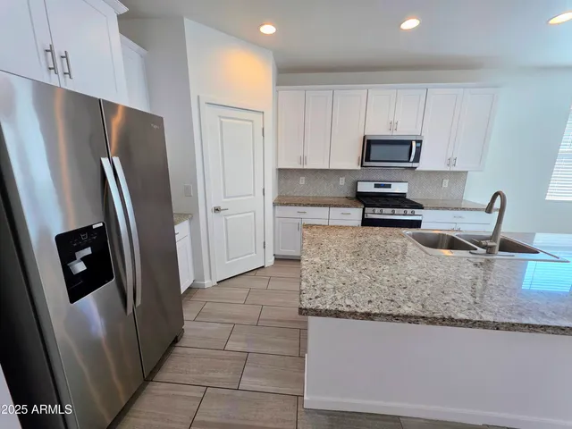 a kitchen with stainless steel appliances granite countertop a refrigerator a stove and a sink