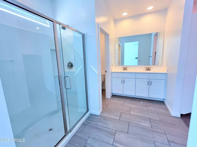 a bathroom with a glass door shower a sink and a mirror