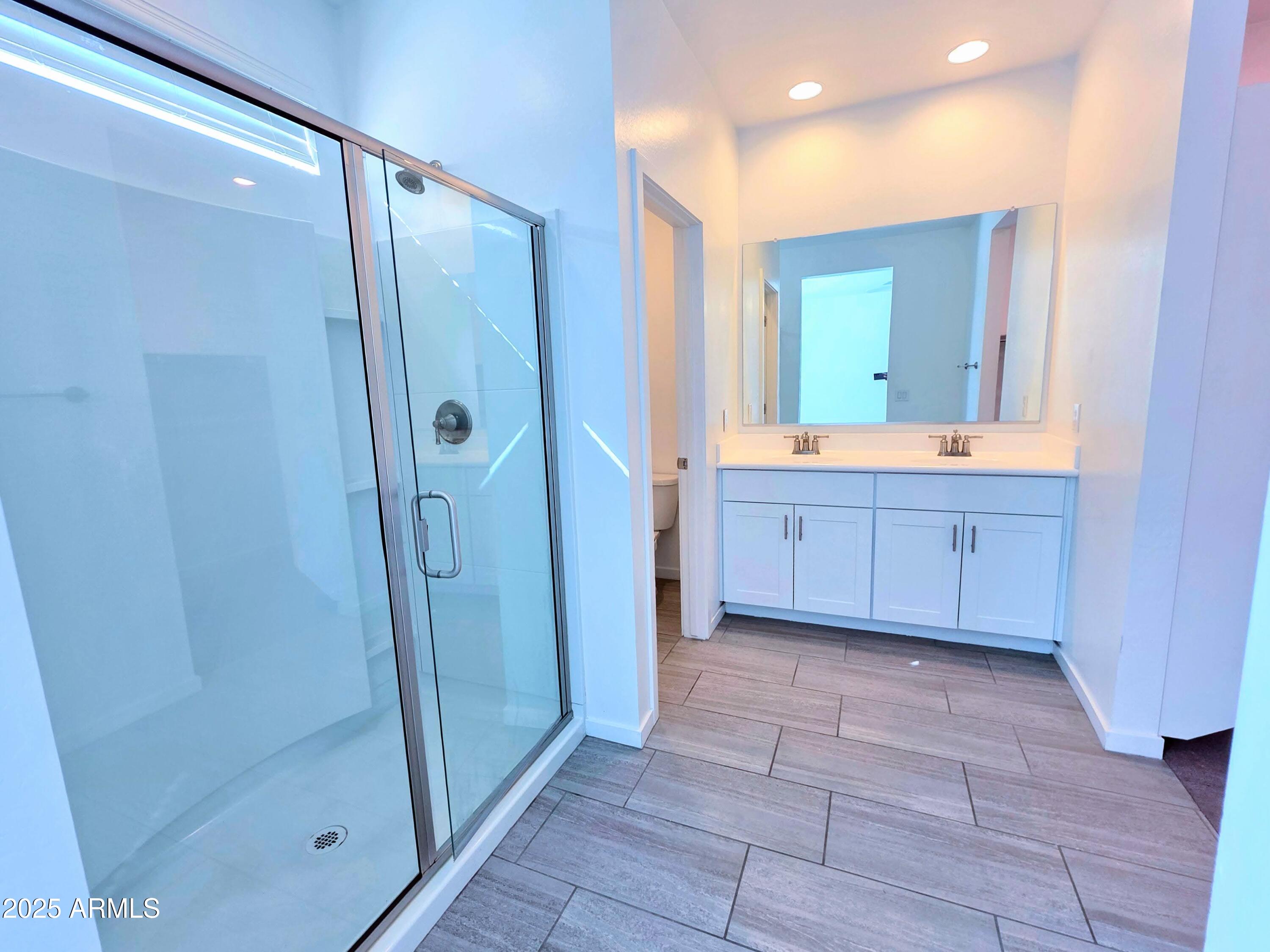 4214 North 68th Lane Phoenix, AZ 85043 - Photo 5 of 13 a bathroom with a glass door shower a sink and a mirror