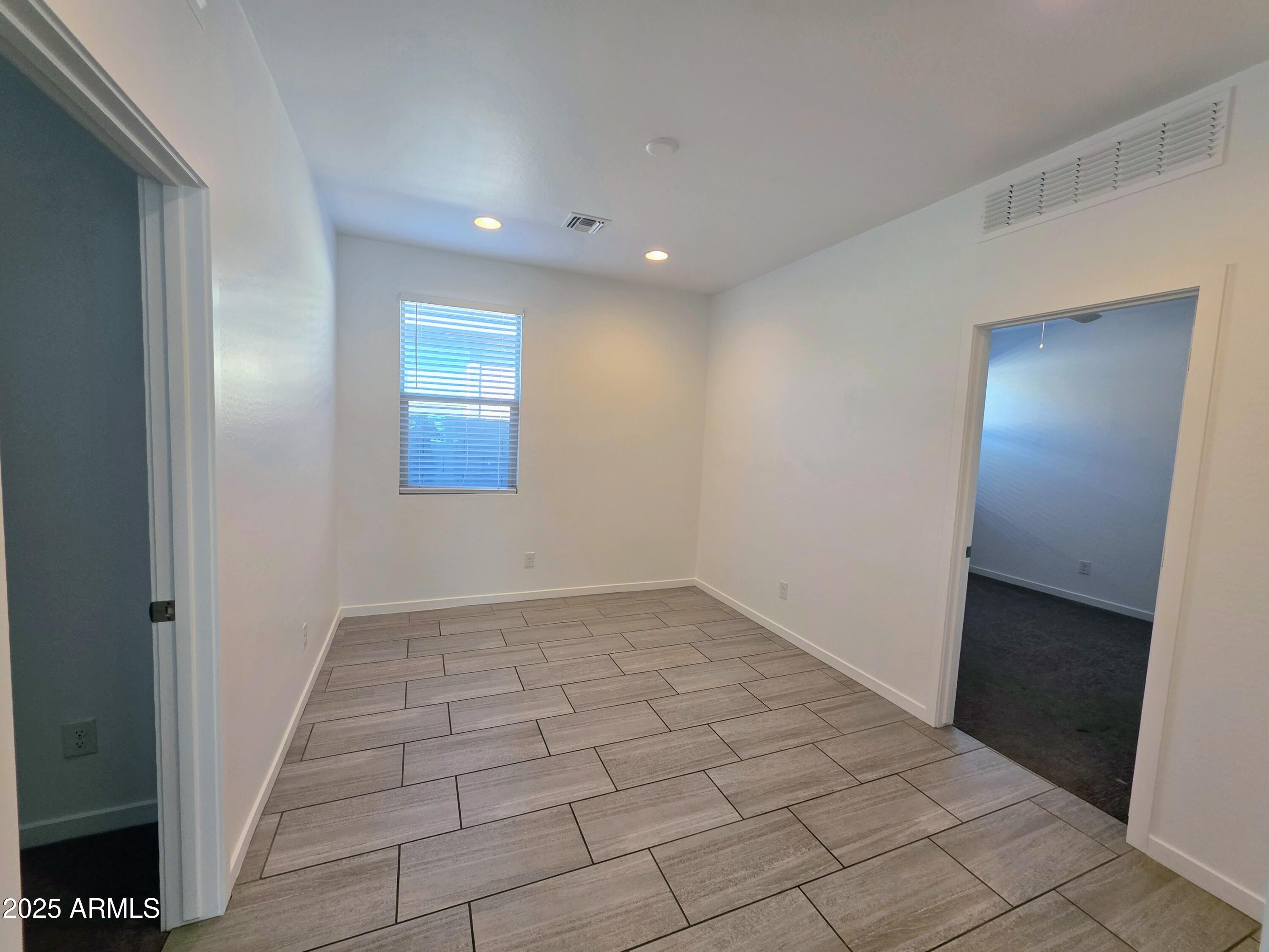 4214 North 68th Lane Phoenix, AZ 85043 - Photo 7 of 13 an empty room with white walls and tiles