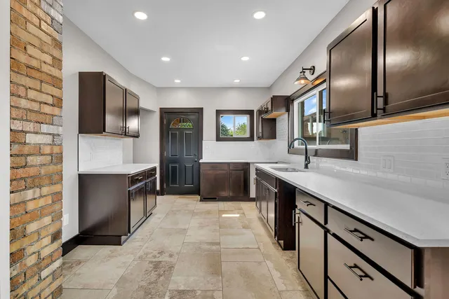 a large kitchen with stainless steel appliances granite countertop a large counter top a stove and a sink
