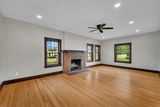 an empty room with windows a fireplace and a chandelier fan