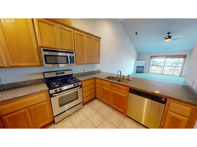 a kitchen with kitchen island granite countertop a sink cabinets and stainless steel appliances