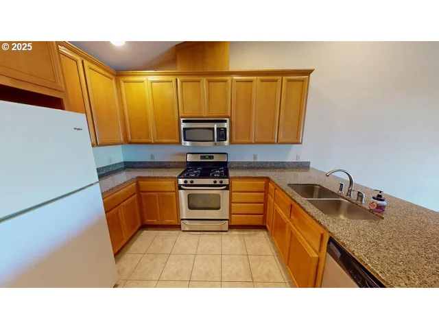 a kitchen with stainless steel appliances kitchen island granite countertop a sink dishwasher stove top oven and microwave with cabinets