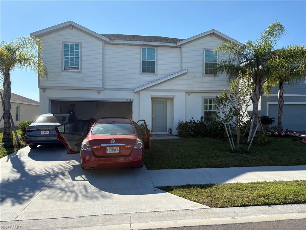 Traditional-style house featuring a front yard, driveway, and a garage