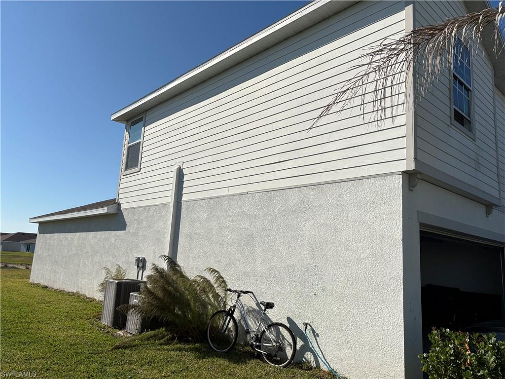 19891 Green Pasture Road Lehigh Acres, FL 33936 - Photo 2 of 5 View of home's exterior with stucco siding and a lawn