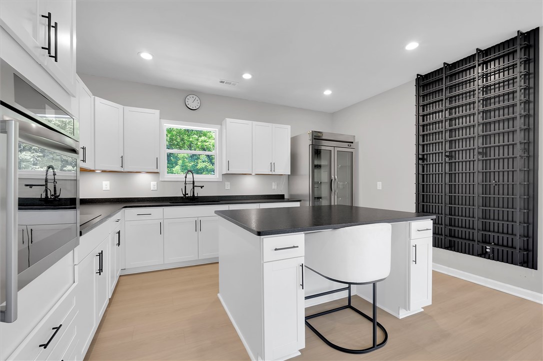 159 Cherokee Trail Easley, SC 29640 - Photo 13 of 38 Modern kitchen with white cabinetry and dark countertops, featuring a central island for dining and food preparation.