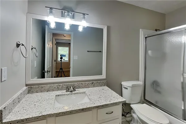 a bathroom with a granite countertop sink toilet a mirror and shower