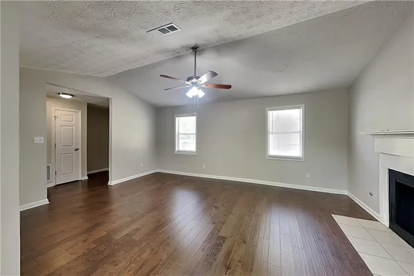 an empty room with wooden floor chandelier and windows