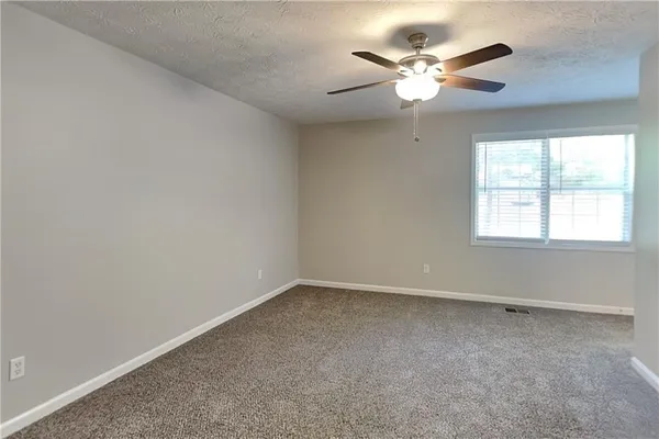 an empty room with a window and a ceiling fan