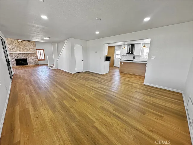 a view of empty room with kitchen and fireplace