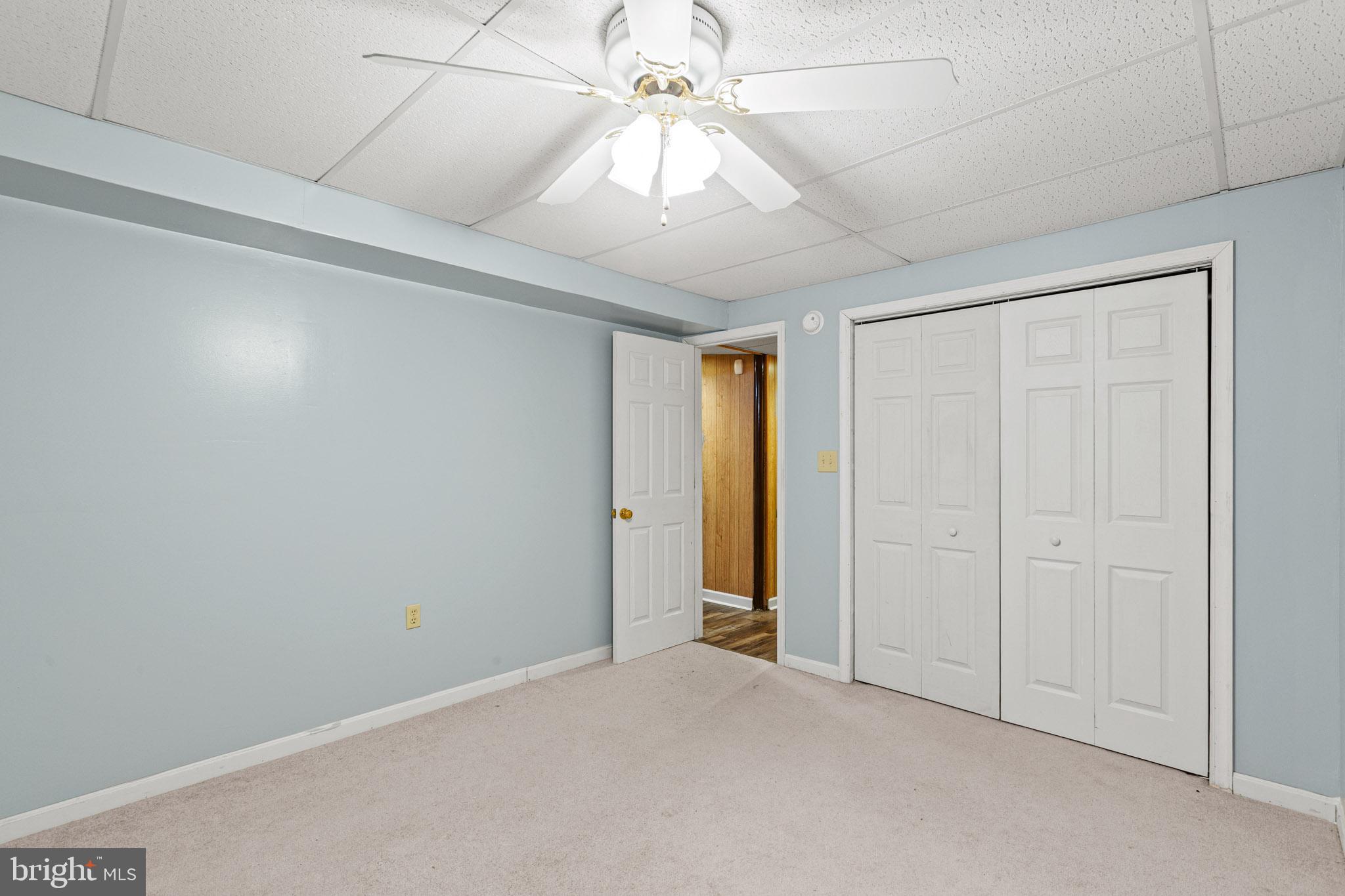 11660 Big Sandy Run Road Lusby, MD 20657 - Photo 13 of 30 an empty room with a chandelier fan and windows
