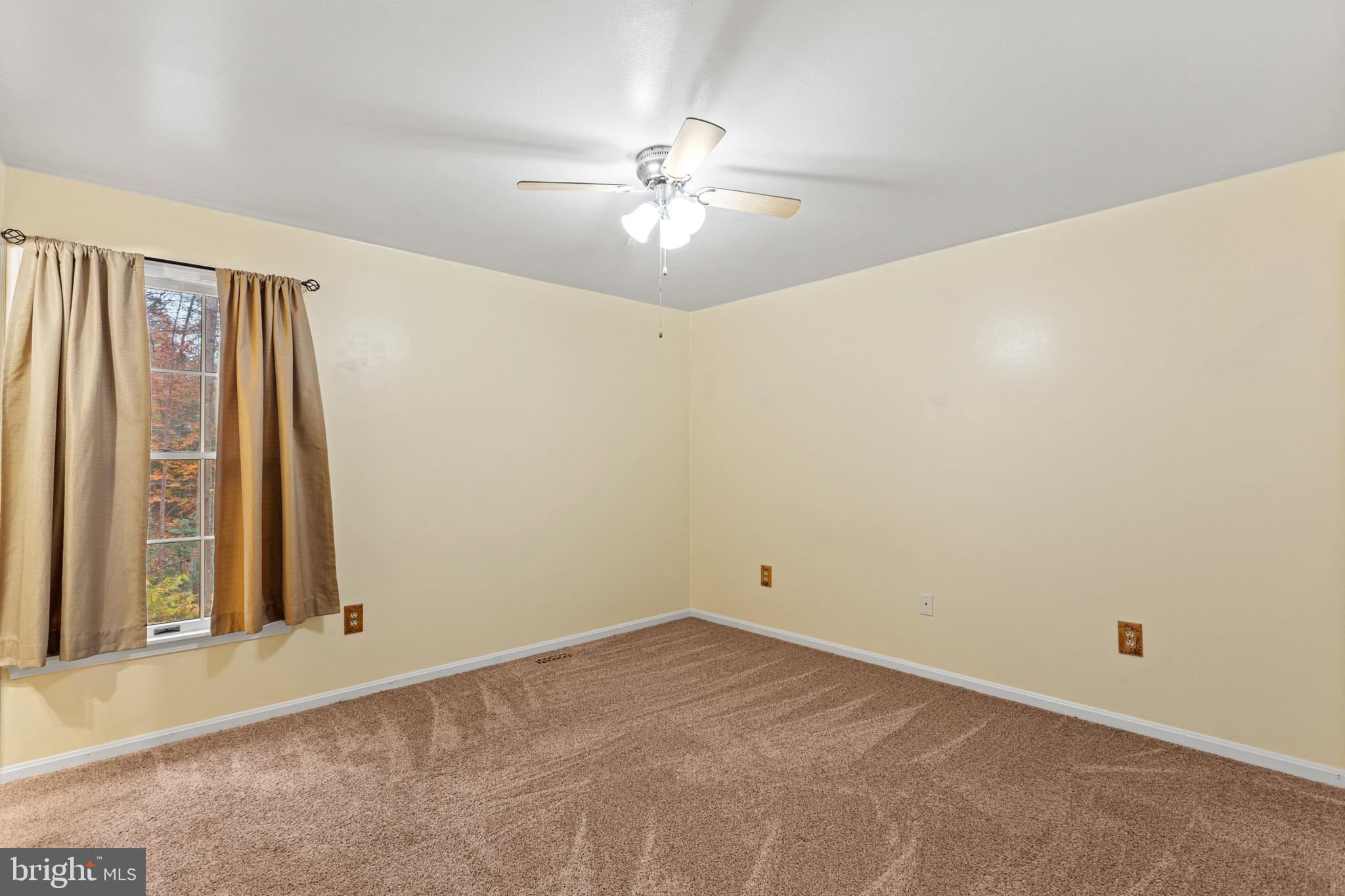 11660 Big Sandy Run Road Lusby, MD 20657 - Photo 21 of 30 an empty room with a chandelier fan and windows