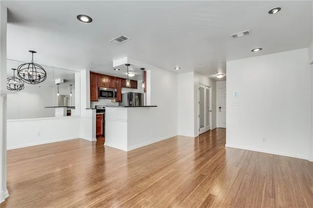 a view of a kitchen and an empty room with wooden floor