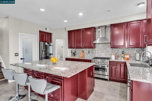 a kitchen with granite countertop kitchen island stainless steel appliances a stove top oven a sink and a refrigerator