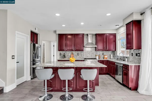 a kitchen with stainless steel appliances granite countertop a table chairs sink refrigerator and cabinets
