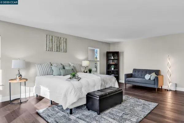 a bedroom with a bed a couch and wooden floor