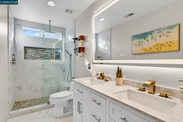 a bathroom with a granite countertop sink mirror vanity shower and toilet