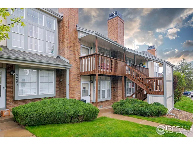 a view of a brick house with a small yard plants and large tree