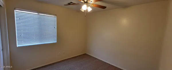 an empty room with a window and a fan